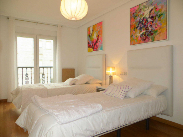 Dormitorio luminoso de los Apartamentos Jardines de Lugo con cama doble y acceso a balcón
